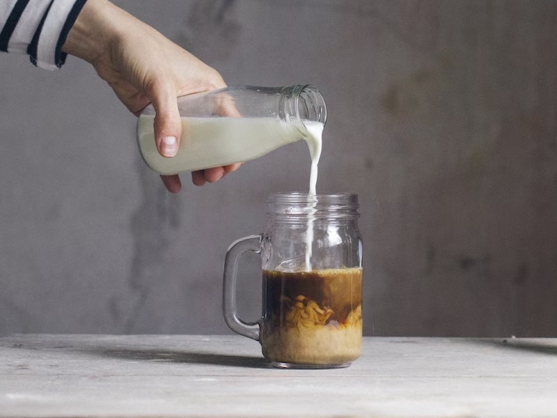 adding creamer to a coffee